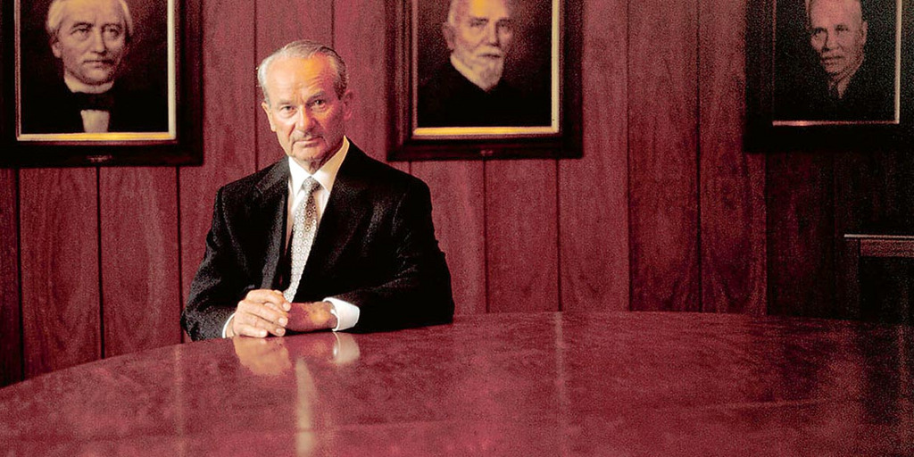 The founder Reinhard Mohn sitting in front of portraits of his ancestors.